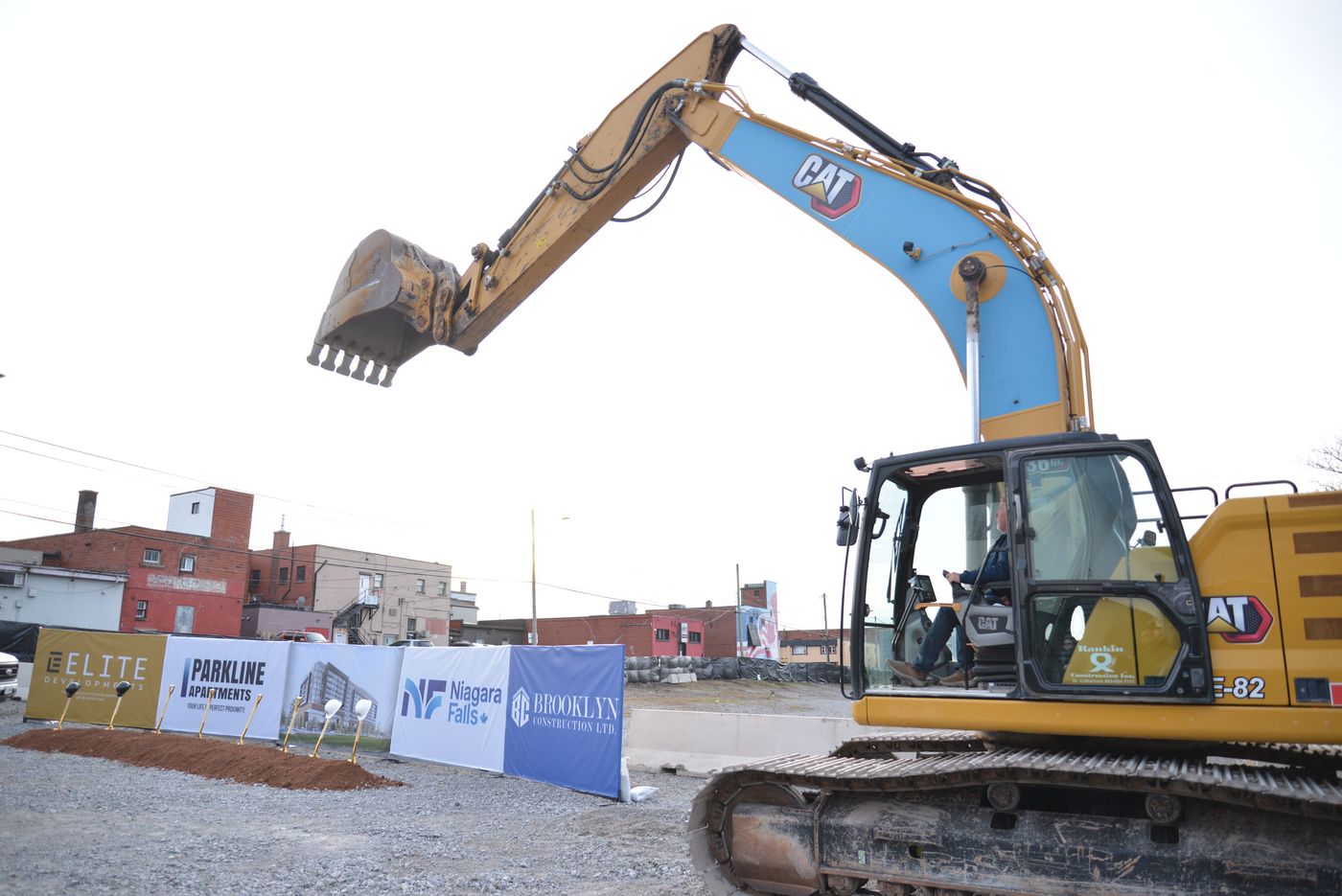 An excavator reaching across the cleared 4500 Park Street site, with Elite Developments, Parkline Apartments, City of Niagara Falls and Brooklyn Construction banners along the hoarding